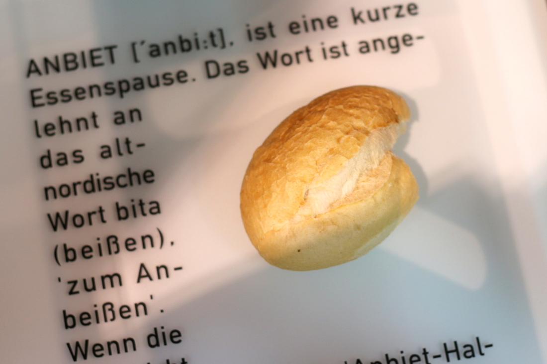 Ein angebissenes Brötchen steht für "Anbiet", die kleine Pause der Hafenarbeiter