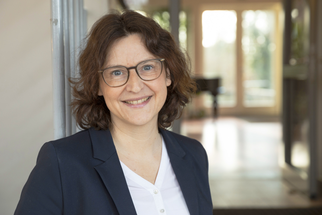 Ein Porträt einer lächelnden Frau mit lockigen halblangen Haaren und Brille Ein Porträt einer lächelnden Frau mit lockigen halblangen Haaren und Brille