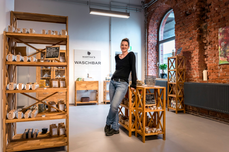 Claudia Schreiber steht in ihrer Seifenmanufaktur umgeben von Produkten Claudia Schreiber steht in ihrer Seifenmanufaktur umgeben von Produkten