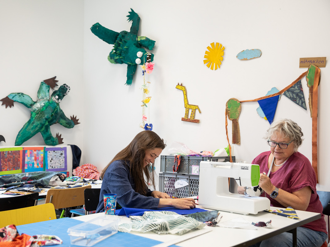 In einem Atelier sitzen zwei Frauen an einer Nähmaschine und arbeiten In einem Atelier sitzen zwei Frauen an einer Nähmaschine und arbeiten