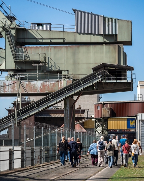 Eine Gruppe von Besucherinnen und Besuchern geht bei ihrer Tour am Fabrikenufer entlang. Eine Gruppe von Besucherinnen und Besuchern geht bei ihrer Tour am Fabrikenufer entlang.