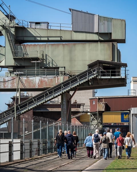 Eine Gruppe von Besucherinnen und Besuchern geht bei ihrer Tour am Fabrikenufer entlang.