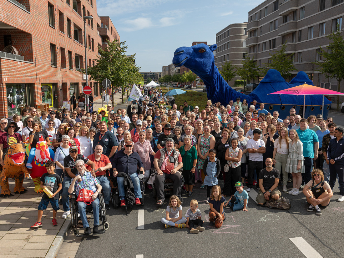 Eine große Menschengruppe ist auf einer Straße in der Überseestadt versammelt, im Hintergrund steht das Kamel der Blauen Karawane Eine große Menschengruppe ist auf einer Straße in der Überseestadt versammelt, im Hintergrund steht das Kamel der Blauen Karawane
